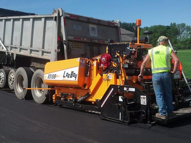 Dump truck and asphalt paver being used for new roadway paving